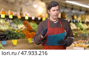 Man seller take inventory with list in vegetable shop. Стоковое видео, видеограф Яков Филимонов / Фотобанк Лори