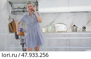 Housewife talking on smartphone and vacuuming the room at the same time. Стоковое видео, видеограф Яков Филимонов / Фотобанк Лори