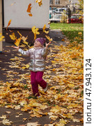 A 5 year old girl delights in tossing colorful autumn leaves into the air while playing on a lively playground. Стоковое фото, фотограф Aleksandr Golubev / Фотобанк Лори