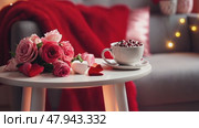 A cozy reading nook set for Valentine's Day, with a plush chair draped in a red blanket, heart-shaped fairy lights surrounding the area, and a small table with chocolates and a rose. Стоковое AI-видео, аниматор Ирина Старикова / Фотобанк Лори