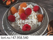 Creamed cottage cheese with raspberries. An easy healthy breakfast. A bowl filled with grainy, creamy cottage cheese is garnished with bright yellow and red raspberries. Стоковое фото, фотограф Оксана Медведева / Фотобанк Лори