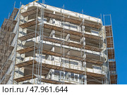 Фасад здания с установленными строительными лесами. Building under construction in scaffolding around the house for cement plastering work on the high outer wall. Стоковое фото, фотограф Татьяна Д / Фотобанк Лори