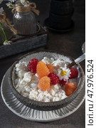 Creamed cottage cheese with raspberries. An easy healthy breakfast. A bowl filled with grainy, creamy cottage cheese is garnished with bright yellow and red raspberries. Стоковое фото, фотограф Оксана Медведева / Фотобанк Лори