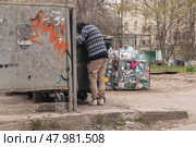 A homeless man digs through garbage in search of food. Стоковое фото, фотограф Михаил Яковлев / Фотобанк Лори