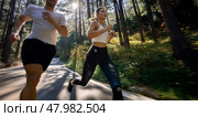 Wide angle shot of a couple running in the forest trail. Intentional motion blur. Front view. Стоковое AI-изображение, AI-художник Катерина Ковалева / Фотобанк Лори