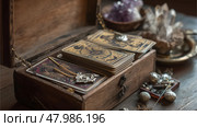 Mystical tarot cards and vintage jewelry displayed in a wooden box at a cozy magical setting. Стоковое AI-изображение, AI-художник Сергей Толмачёв / Фотобанк Лори