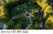 Exploring a modern labyrinth garden with lush greenery and winding pathways in an urban setting. Стоковое AI-изображение, AI-художник Сергей Толмачёв / Фотобанк Лори