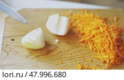 Chef chopping onion next to grated carrots on wooden cutting board. Стоковое видео, видеограф Константин Шишкин / Фотобанк Лори
