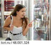 Interested young woman viewing various swords placed on display case. Стоковое фото, фотограф Яков Филимонов / Фотобанк Лори
