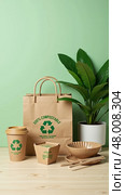 Brown bag with the words 100 % compostable on it is on a table with a potted. Стоковое AI-изображение, AI-художник Sergey Grishin / Фотобанк Лори
