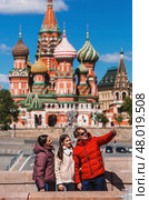 Russia, Moscow, April 28, 2025. Foreigners in Russia. Tourists are photographed against the backdrop of the Kremlin and famous sights of Moscow. Tourism and travel. Редакционное фото, фотограф Photojuli / Фотобанк Лори