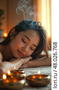 Young woman relaxing at spa with incense smoke and warm candlelight atmosphere. Стоковое AI-изображение, AI-художник Mariya Suranova / Фотобанк Лори