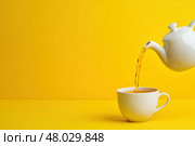 Чай наливается в чашку на ярком фоне. Стоковое AI-изображение, AI-художник Александр Жуков / Фотобанк Лори