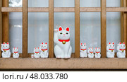 Tokyo, Japan - Sep 30 2024, A close-up view of many multi-sized white beckoning cat figure of Maneki neko with red ears and noses displayed at Gotokuji Temple, without people, at daytime, Tokyo, Japan. Стоковое фото, фотограф Сергей Богомяко / Фотобанк Лори