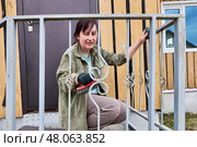 Wire brush is used to clean decorative ironwork on metal railing during surface preparation on front porch before painting or rust treatment. Стоковое фото, фотограф Владимир Григорьев / Фотобанк Лори