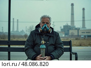 Мужчина в противогазе, озабоченное настроение, сидит на скамейке рядом с промышленной зоной, фон загрязнения. Стоковое AI-изображение, AI-художник Елена Болотина / Фотобанк Лори