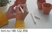 Crafting personalized plant labels: handwriting on terracotta pots with white marker. Стоковое видео, видеограф Zakharova Natasha / Фотобанк Лори