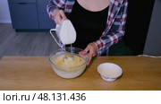 Girl in checkered shirt mixing dough with mixer and adding raisins in transparent bowl. Стоковое видео, видеограф Катерина Белякина / Фотобанк Лори