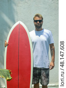 A surfer riding the waves with a bright red surfboard on a beautiful summer day at the beach. Стоковое фото, фотограф Женя Канашкин / Фотобанк Лори