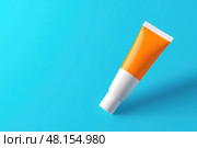 Orange white tube with suntan lotion, cosmetic face cream or hand cream, shower gel, against the blue turquoise color plain studio background. Blank plastic package mockup. Skincare product template. Стоковое AI-изображение, AI-художник Марина Демидюк / Фотобанк Лори