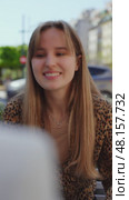 Young blond woman in leopard print top conversing cheerfully while seated at outdoor cafe table, jewelry complementing relaxed urban setting. Стоковое видео, видеограф Данил Руденко / Фотобанк Лори