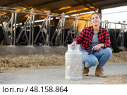 Cheerful girl posing with milk can in cowshed on dairy farm. Стоковое фото, фотограф Яков Филимонов / Фотобанк Лори