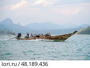 Thailand, Khao Sok 2025 14 02: Cruise the calm waters of Thailand on a long-tail boat, exploring the beauty of lakes and mountains during a scenic tour. The female helmsman Loki talks about gender equality in Thailand. Стоковое фото, фотограф Владимир Разгуляев / Фотобанк Лори