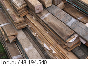 Bundles of old boards are tied with transparent tape and stacked in a pile. Старые доски подготовлены для транспортировки и утилизации или повторного использования. Вид сверху. Стоковое фото, фотограф Ольга Солопова / Фотобанк Лори