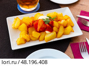 Close up of traditional spanish patatas bravas on plate on tablecloth. Стоковое фото, фотограф Яков Филимонов / Фотобанк Лори