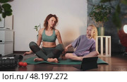 Family stretching on yoga mats during indoor workout session. Mom and daughter do fitness exercises at home, promoting health and flexibility with simple daily routine. Sideways bend exercise. Стоковое видео, видеограф Енваев Андрей / Фотобанк Лори