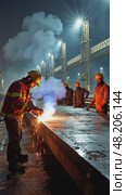 A modern shipyard, workers in hard hats welding massive steel plates, with cranes and scaffolding in the background. Стоковое AI-видео, аниматор Sergey Grishin / Фотобанк Лори