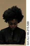 A woman in a black suit reflects with her head bowed, showcasing her natural, voluminous hair against a light background. Стоковое AI-изображение, AI-художник Данила Большаков / Фотобанк Лори
