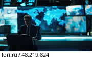 An analyst focuses intently at his workstation amidst vibrant digital dashboards displaying global data. Стоковое AI-изображение, AI-художник Данила Большаков / Фотобанк Лори