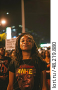 A determined activist stands confidently at the forefront of a night march advocating for social justice. Стоковое AI-изображение, AI-художник Данила Большаков / Фотобанк Лори