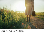 Девушка идет с винтажной сумкой по полю в лучах солнца. Стоковое фото, фотограф Надежда Парижская / Фотобанк Лори