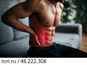 Inflammation of appendicitis, stomach ulcer, bloating, muscular man with abdominal pain suffering at home, symptoms of gastritis, diseases of the digestive system, health problems concept. Стоковое AI-изображение, AI-художник Станислав Тарко / Фотобанк Лори