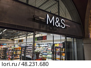 Marks and Spencer store front sign illuminated above entrance. London, UK, 29 March 2024. Редакционное фото, фотограф Zydrius Tartenis / Фотобанк Лори