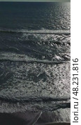 Warm sunlight glimmering across rippling ocean surface, gentle waves lapping sandy shoreline, embodying tranquil coastal serenity. Стоковое видео, видеограф ILIA GOROKHOV / Фотобанк Лори
