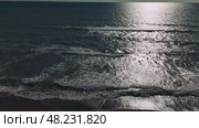 Warm sunlight glimmering across rippling ocean surface, gentle waves lapping sandy shoreline, embodying tranquil coastal serenity. Стоковое видео, видеограф ILIA GOROKHOV / Фотобанк Лори