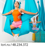 Young women making antigravity yoga exercises with group of people. Стоковое фото, фотограф Яков Филимонов / Фотобанк Лори