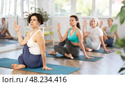 Hispanic woman performing seated twisting asana Matsyendrasana. Стоковое фото, фотограф Яков Филимонов / Фотобанк Лори