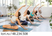 Girl performing seated side bending asana Parsva Sukhasana. Стоковое фото, фотограф Яков Филимонов / Фотобанк Лори