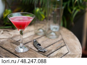 Red cocktail with ice in a stemmed glass on a wooden surface. Стоковое фото, фотограф Татьяна Яцевич / Фотобанк Лори