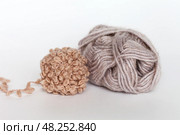 Close-up of two wool yarn for hand knitting in beige colors . Soft and warm wool-acrylic blend yarn in skein and unusual fluffy voluminous boucle yarn in ball on white background. Knitting as a hobby. Стоковое фото, фотограф Виктория Катьянова / Фотобанк Лори
