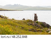 Lake Baikal on a foggy summer day. Traditional pyramid of stones left by tourists on the shore of the Khul Bay of Olkhon Island. Beautiful summer landscape. Travel and hiking along the lake shore. Стоковое фото, фотограф Виктория Катьянова / Фотобанк Лори