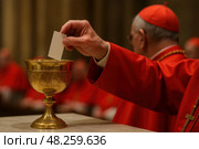 Elderly caucasian male clergy participating in religious voting ceremony with golden chalice. conclave. Стоковое AI-изображение, AI-художник Башкирова Анна / Фотобанк Лори