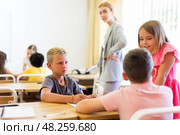 Concentrated preteen girls and boys solving teacher assignments in groups. Стоковое фото, фотограф Яков Филимонов / Фотобанк Лори