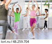 Positive teenage girl practicing ballet positions standing in row with others. Стоковое фото, фотограф Яков Филимонов / Фотобанк Лори