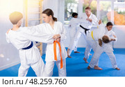 Teenage girl practicing fighting techniques during martial arts sparring with boy. Стоковое фото, фотограф Яков Филимонов / Фотобанк Лори