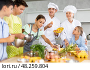 During cooking lesson, male cook tells children about culinary rules, woman assistant helps child. Стоковое фото, фотограф Яков Филимонов / Фотобанк Лори
